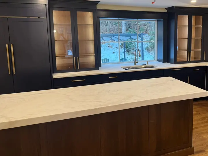 Long island in Calacatta Zambia marble in front of dark cabinets and a window