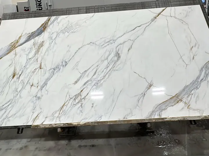 A white slab with gold veins on the cutting table in the shop